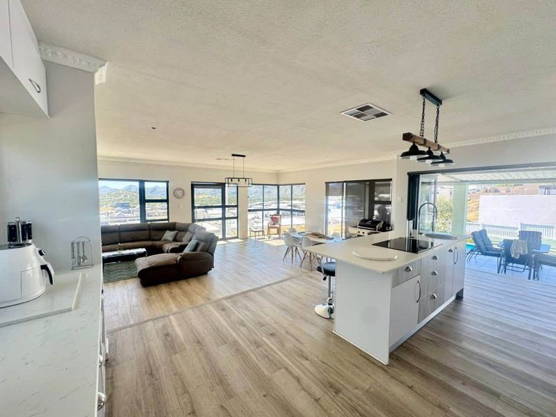Spacious open-plan living area featuring a modern kitchen island, sleek laminate flooring, and large windows offering expansive views and seamless indoor-outdoor flow.