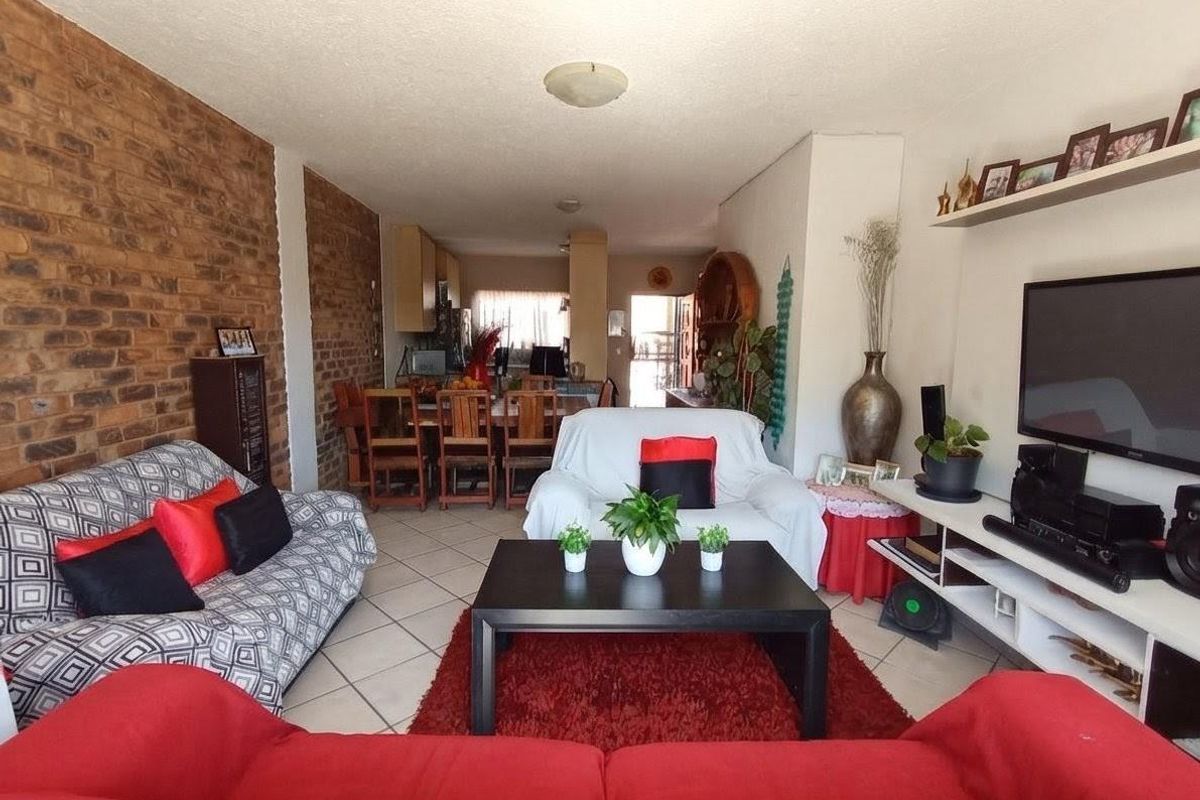 Open plan living and dining area featuring exposed brick wall accents and ceramic floor tiling throughout the space.