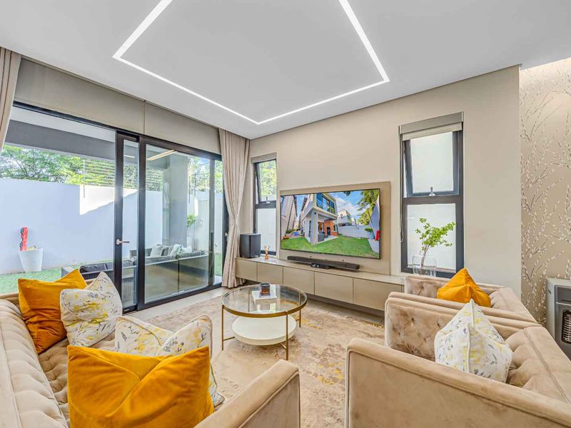 Modern living room featuring recessed LED ceiling lighting, built-in media cabinetry, and large sliding glass doors providing seamless access to the outdoor patio area.