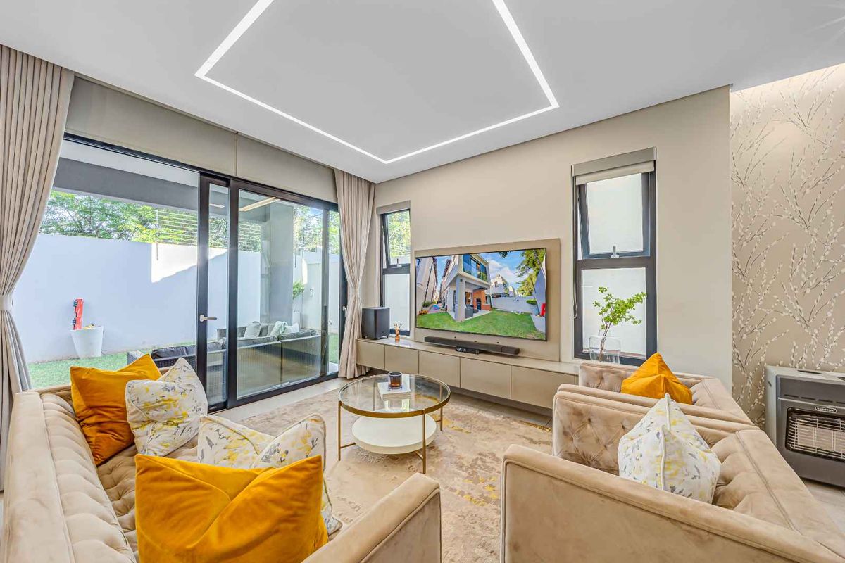 Modern living room featuring recessed LED ceiling lighting, built-in media cabinetry, and large sliding glass doors providing seamless access to the outdoor patio area.