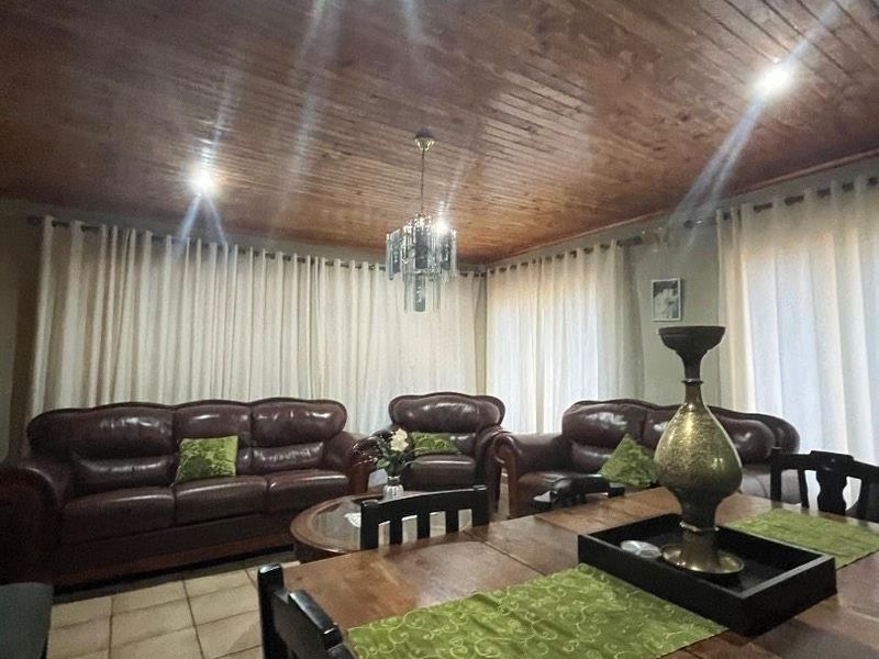 Open plan living and dining area featuring a warm timber tongue and groove ceiling, ceramic tiled flooring, and integrated recessed lighting.