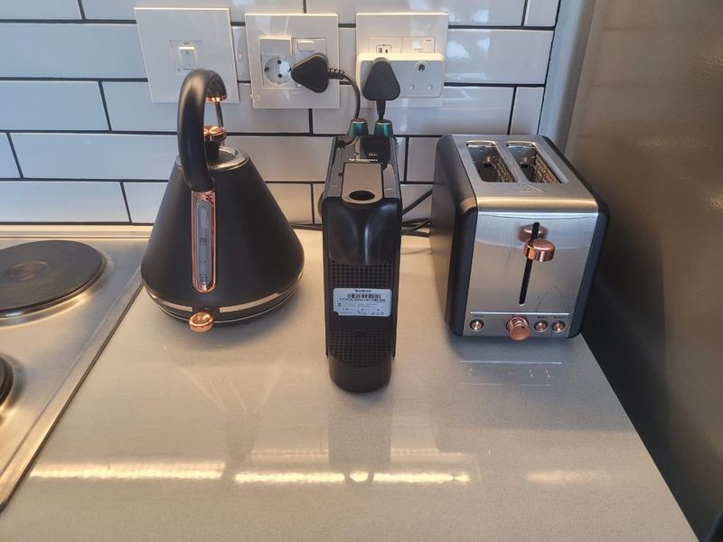 A close-up view of a modern kitchen countertop featuring a subway tile backsplash, stone surface, and integrated electric hob.