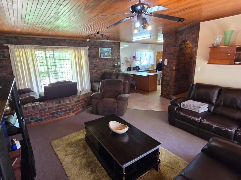 Open plan living area featuring exposed brick walls, timber ceiling, and a connected kitchen space with a central island.
