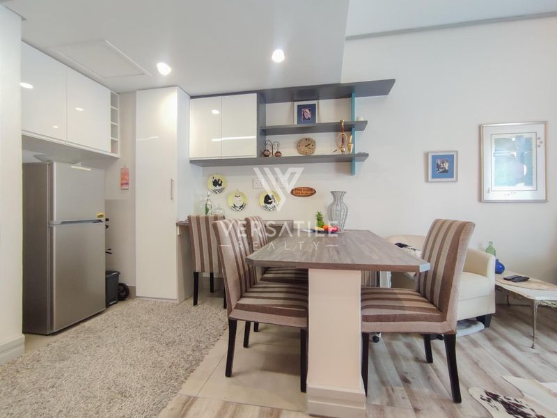 An open-plan living and dining area featuring modern built-in cabinetry, open shelving, and light-toned laminate flooring with recessed ceiling lighting.