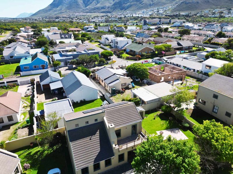 Aerial view of a residential property featuring a tiled roof with solar panels, a balcony, and a well-maintained garden in a suburban estate setting.
