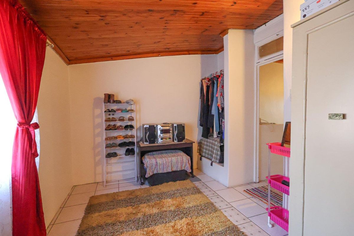 A bedroom featuring a timber-clad ceiling, tiled flooring, and a built-in recessed storage area.