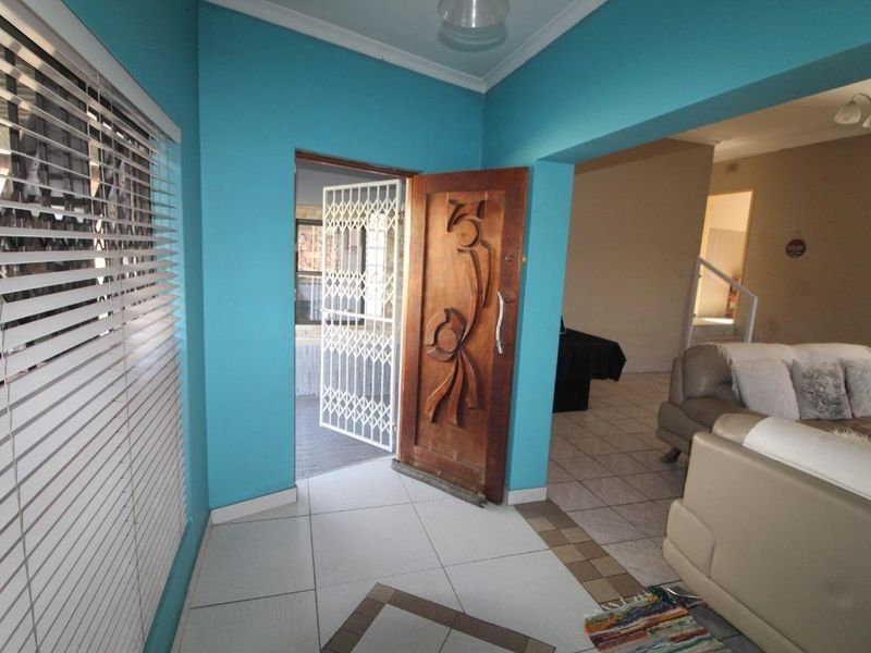 Entrance foyer featuring a decorative carved wooden front door, security gate, and tiled flooring, leading into the main living area.
