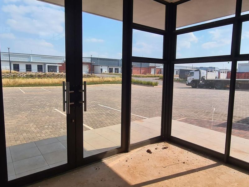 Entrance area featuring large aluminium-framed glass doors and windows, providing clear views of the industrial complex exterior and paved parking area.