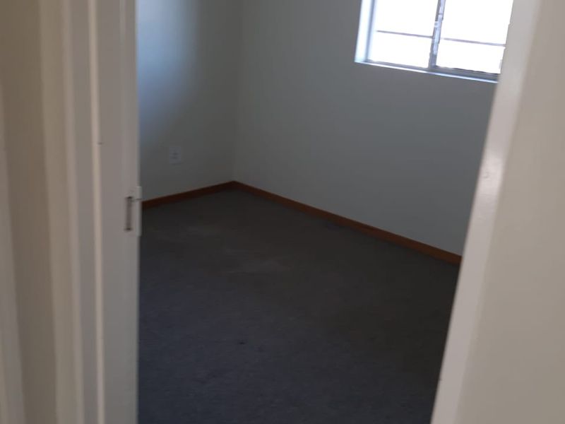 An empty bedroom featuring carpet flooring and a sliding window, providing a blank canvas for potential interior design updates.
