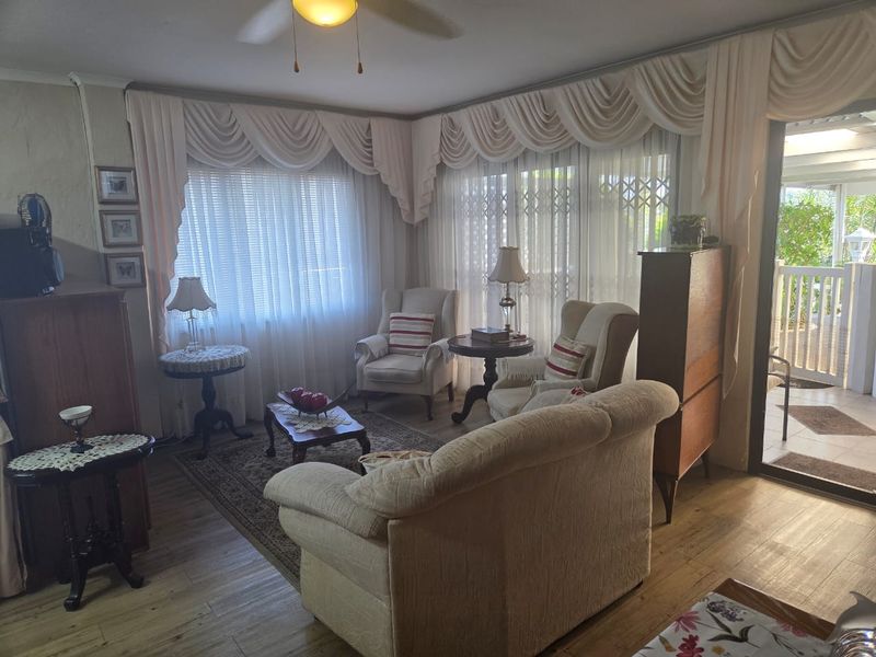 A cozy living room featuring laminate flooring, a ceiling fan, and direct access to an outdoor patio through a sliding glass door.