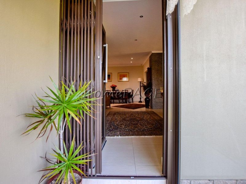 View through the front security gate into the main living area, featuring tiled flooring and recessed lighting.