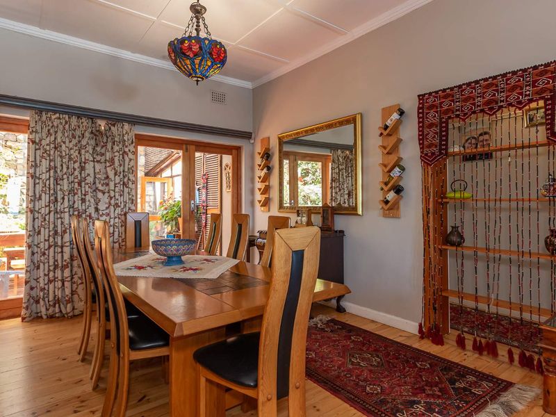 A well-maintained dining room featuring polished timber flooring, coved cornicing, and direct access to an outdoor area through timber-framed french doors.