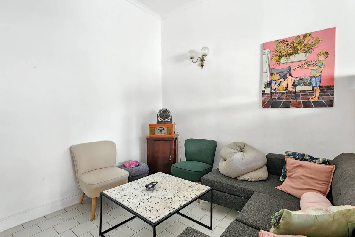 A living room area featuring tiled flooring and a wall-mounted light fixture, providing a neutral base for interior design updates.
