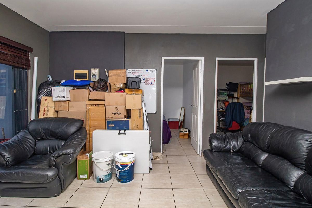 A living room area featuring tiled flooring and access to adjacent rooms, currently used for storage.