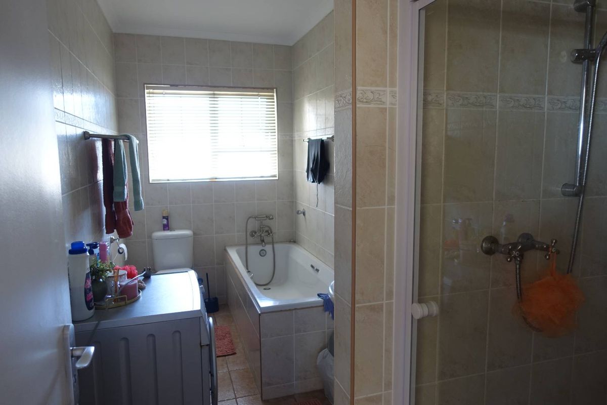 A functional bathroom featuring a built-in bathtub, separate shower enclosure, and tiled walls, providing a practical layout for daily use.