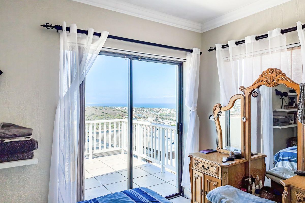 Bedroom featuring a sliding glass door that opens onto a balcony with expansive coastal and landscape views.