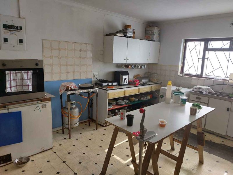 A dated kitchen featuring original cabinetry, a built-in oven, and tiled splashbacks, requiring modernization and renovation to improve functionality and aesthetic appeal.