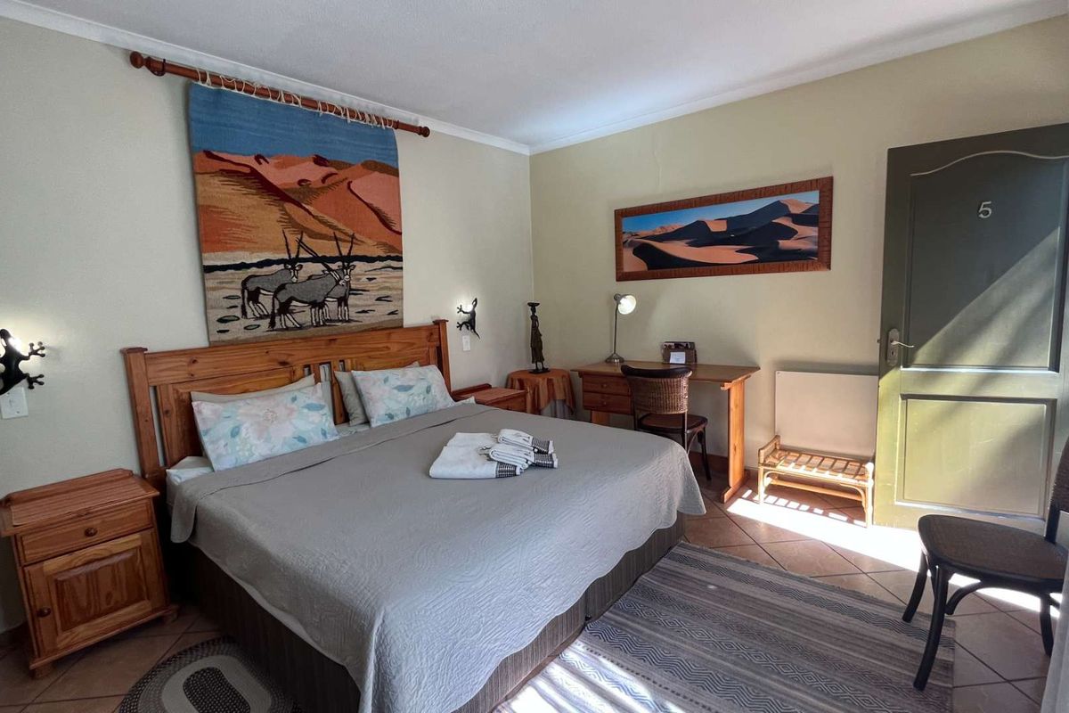A guest bedroom featuring tiled flooring, coving, and a solid wood door, providing a functional and comfortable space for guests.