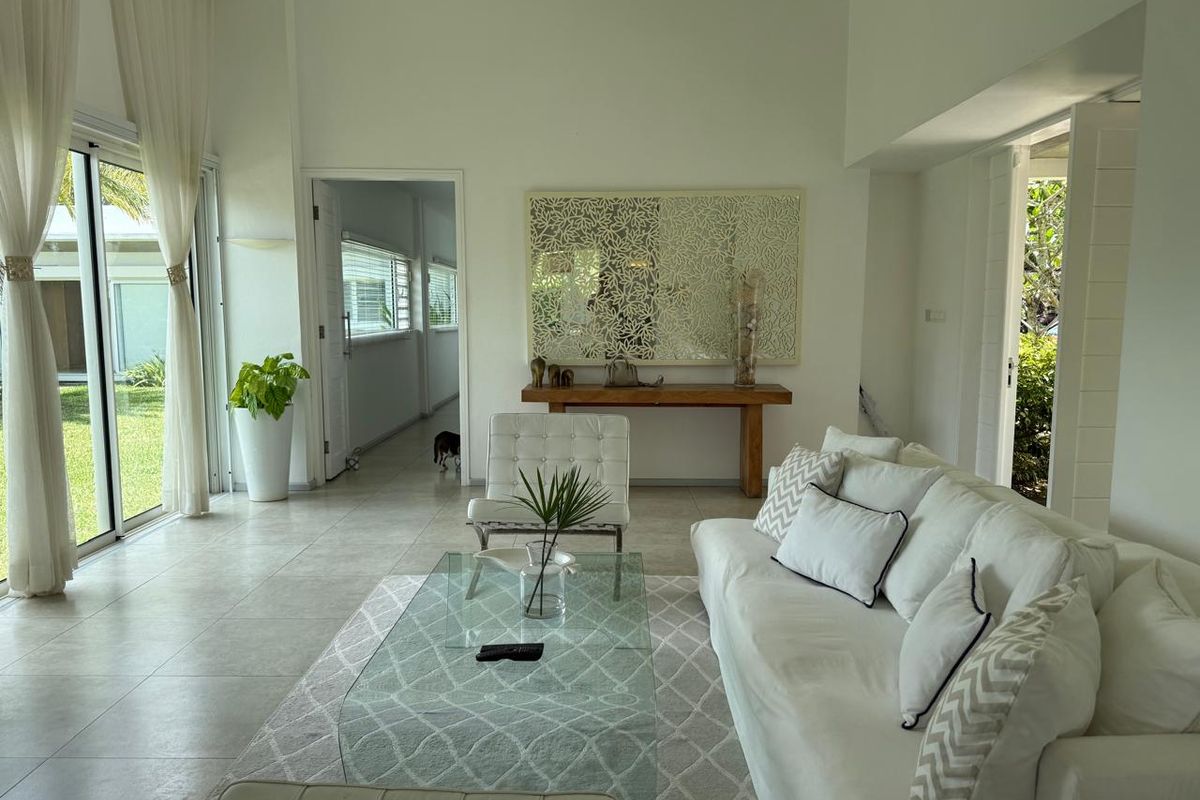 Bright and airy living room featuring large sliding glass doors that open to the garden, tiled flooring, and neutral finishes throughout.