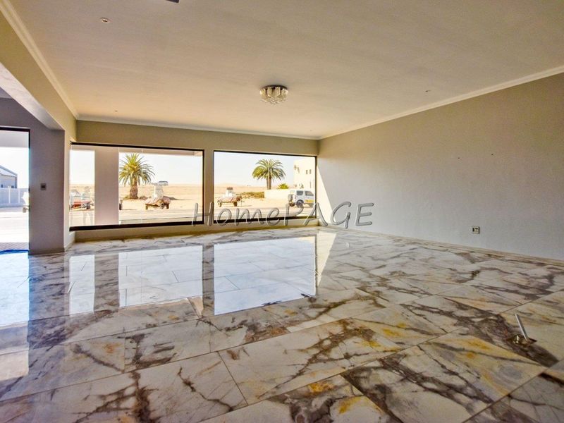 Spacious, empty living area featuring polished marble flooring, neutral walls, and large windows providing ample natural light and exterior views.