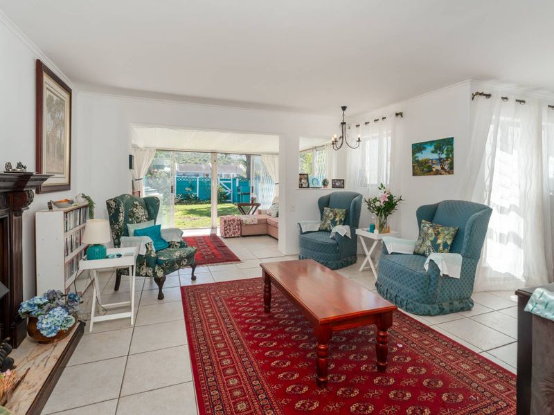 A bright living room featuring tiled flooring, a traditional fireplace, and large sliding glass doors providing access to the rear garden area.