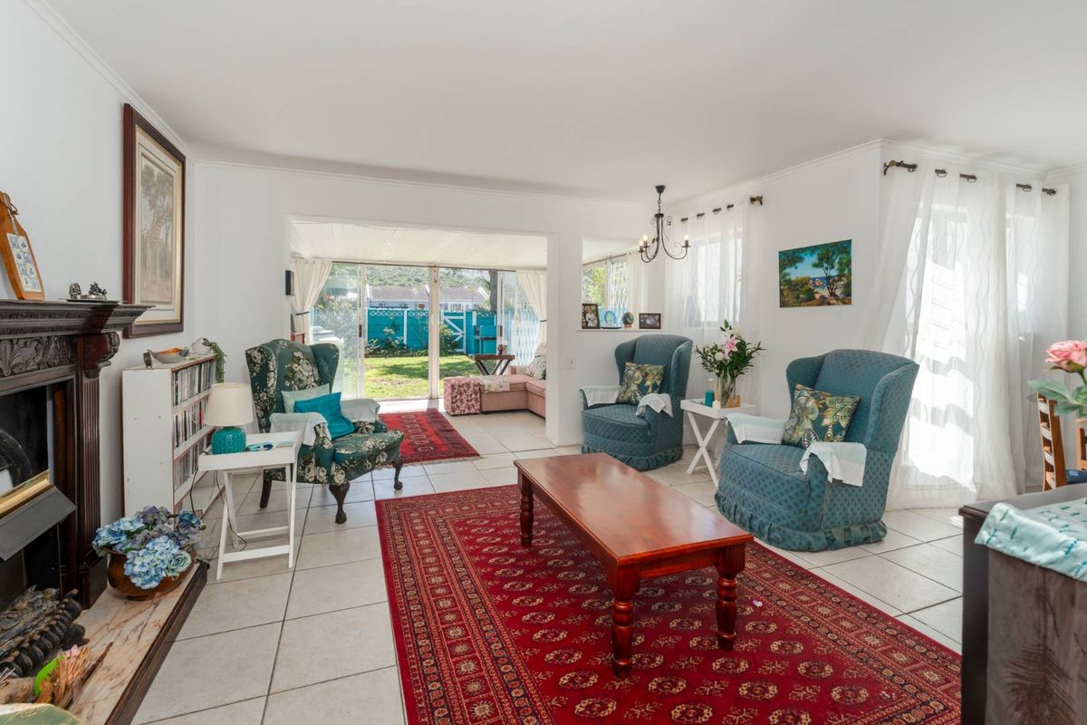 A bright living room featuring tiled flooring, a traditional fireplace, and large sliding glass doors providing access to the rear garden area.