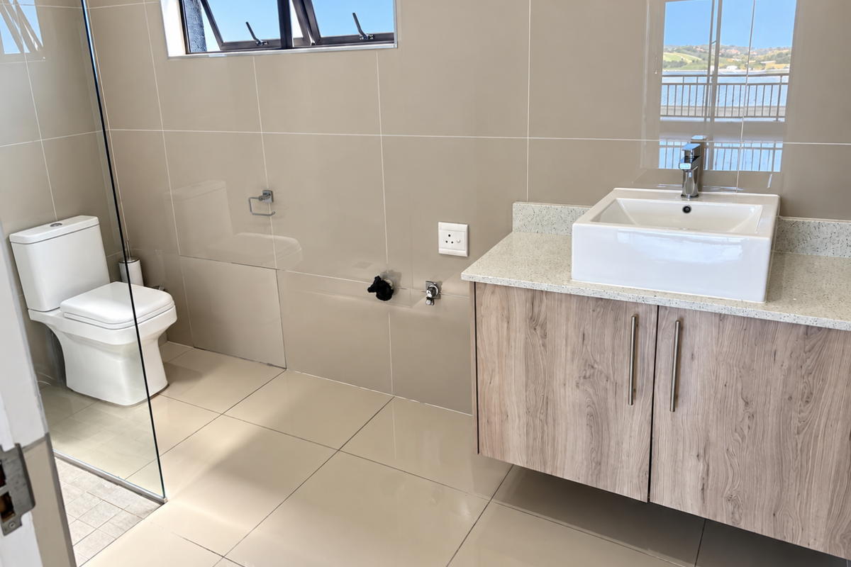 Modern bathroom featuring a wall-mounted wood-finish vanity with a vessel sink, stone countertop, glass shower screen, and neutral floor-to-ceiling wall tiles.