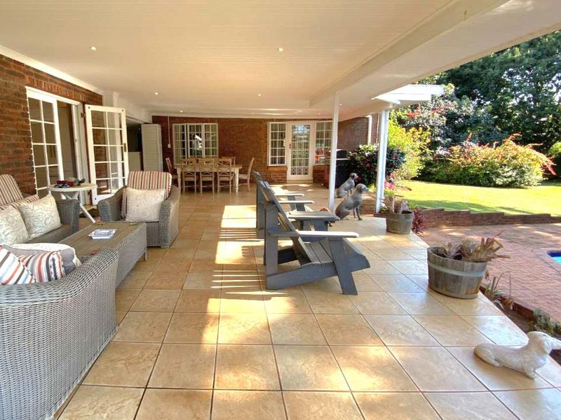 Spacious covered patio featuring tiled flooring and recessed lighting, providing seamless indoor-outdoor flow to the garden and pool area.