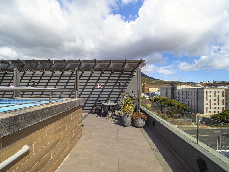 Rooftop terrace featuring a swimming pool, timber pergola, and glass balustrade with panoramic urban views.