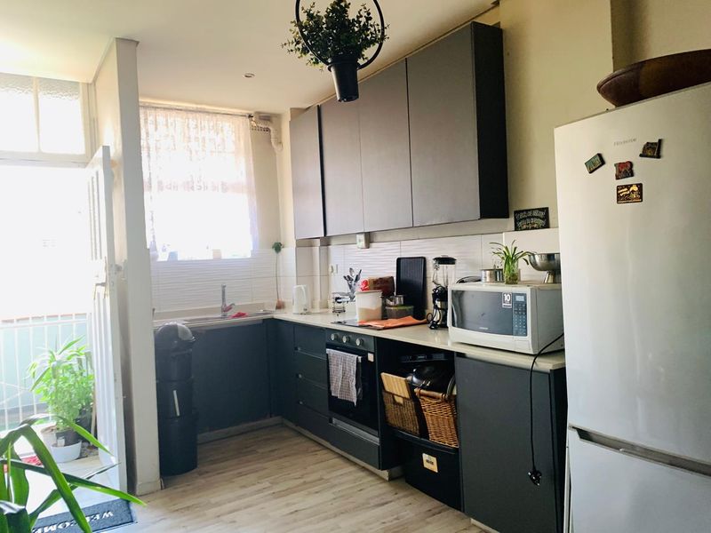 A functional kitchen featuring dark cabinetry, laminate countertops, a built-in oven, and a tiled backsplash, with direct access to an outdoor area.