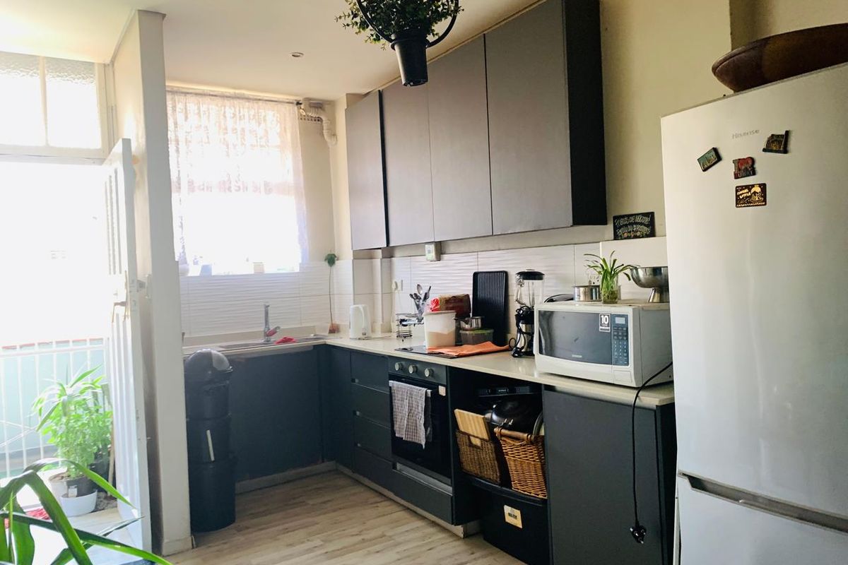 A functional kitchen featuring dark cabinetry, laminate countertops, a built-in oven, and a tiled backsplash, with direct access to an outdoor area.