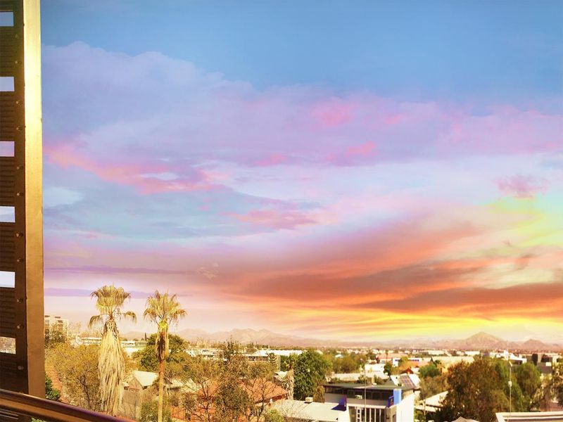 A scenic elevated view overlooking the surrounding neighbourhood and distant mountains at sunset.