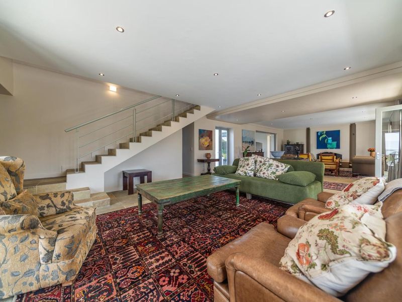 Spacious living area featuring a modern staircase with metal railings and recessed downlighting, offering an open-plan layout with neutral finishes.