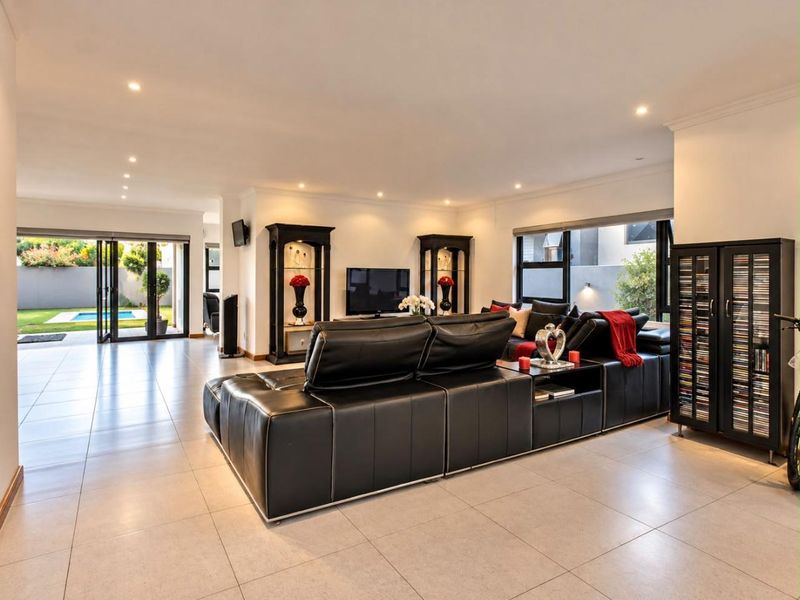 Spacious open-plan living area featuring large format floor tiles, recessed lighting, and seamless access to the outdoor patio and pool area.