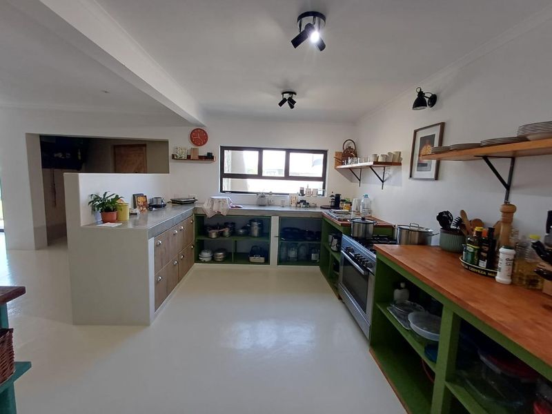 A rustic-style kitchen featuring open shelving, concrete countertops, and a built-in gas oven, offering a functional and characterful cooking space.