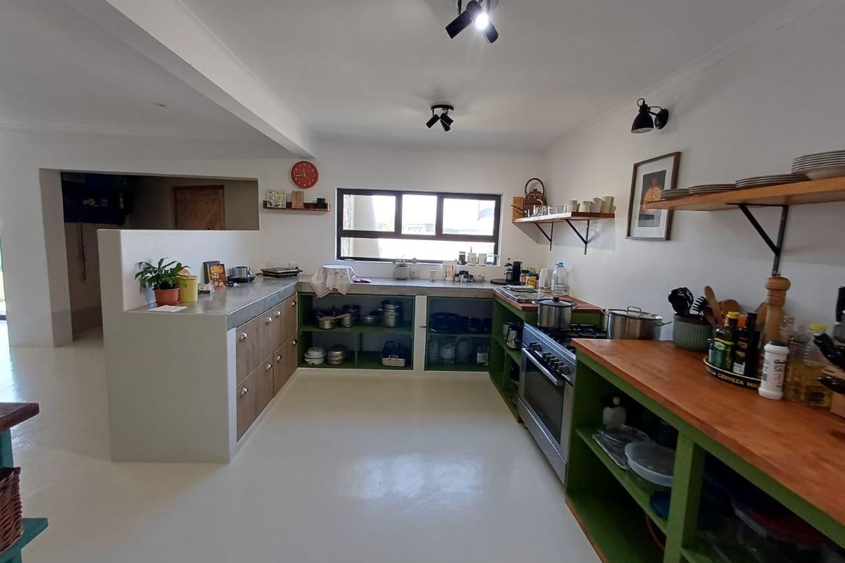A rustic-style kitchen featuring open shelving, concrete countertops, and a built-in gas oven, offering a functional and characterful cooking space.