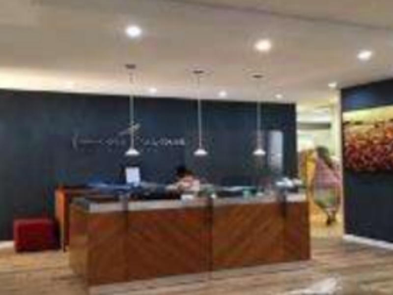 Professional office reception area featuring a wood-paneled desk, modern pendant lighting, and dark accent walls.