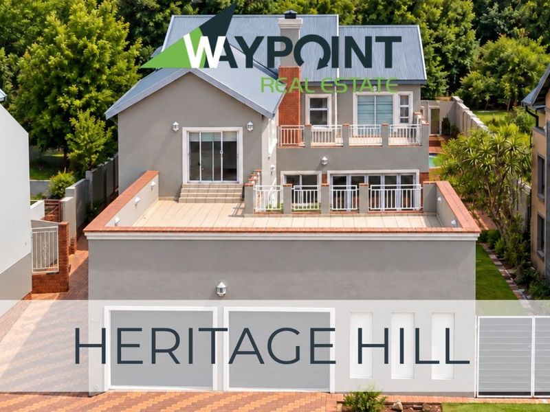 Rear view of a multi-story house featuring a double garage, a spacious tiled terrace, and an upper-level balcony with metal railings.