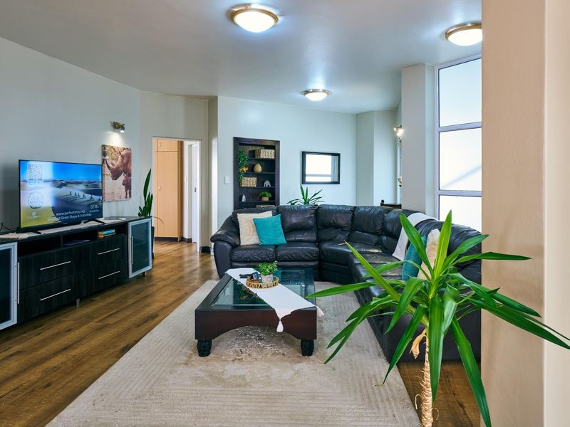 Spacious living room featuring wood-look flooring, large windows for natural light, and recessed ceiling lighting.