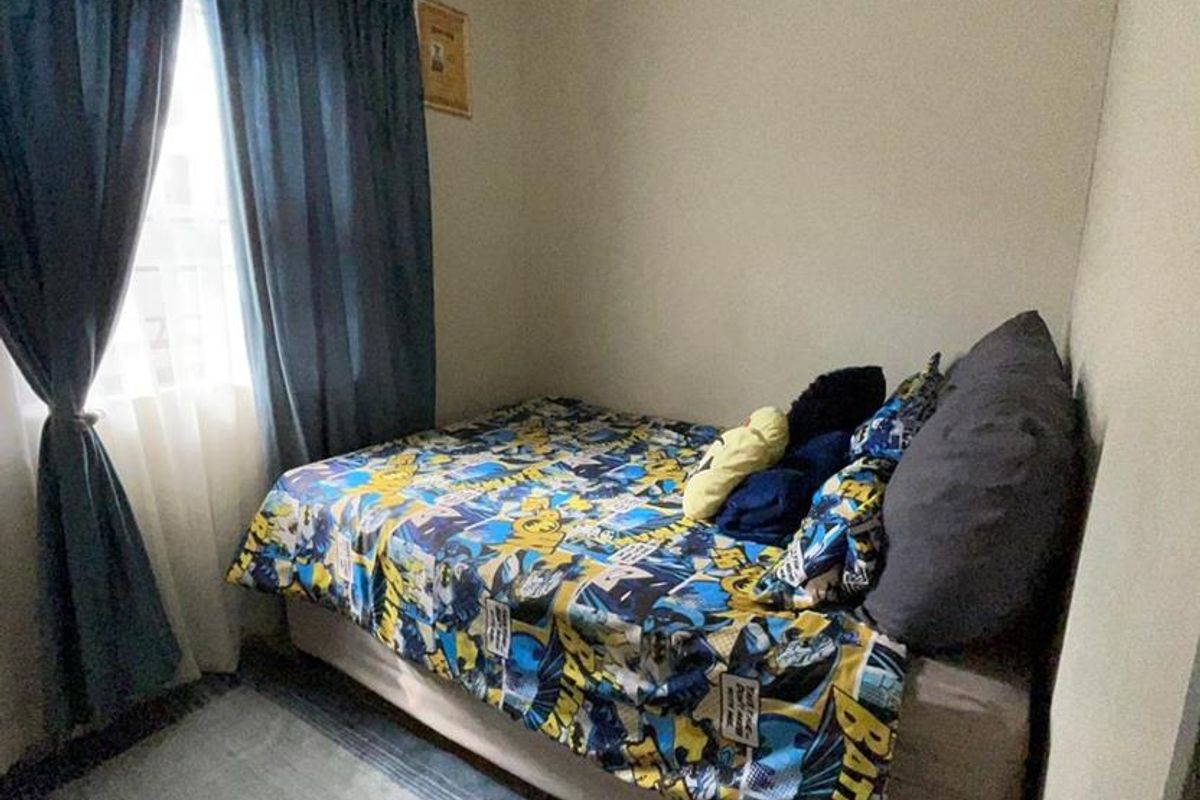 A compact bedroom featuring tiled flooring and coved ceiling details, providing a functional space for a single bed.