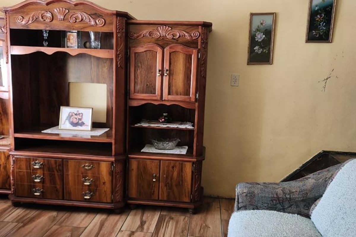 A living room featuring wood-look tiled flooring and coved ceilings, requiring minor wall repairs and a fresh coat of paint to modernize the space.