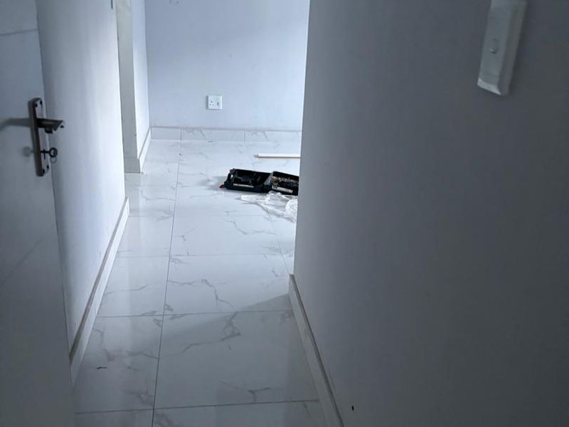 A clean, empty hallway featuring modern marble-look porcelain floor tiles and neutral wall finishes.