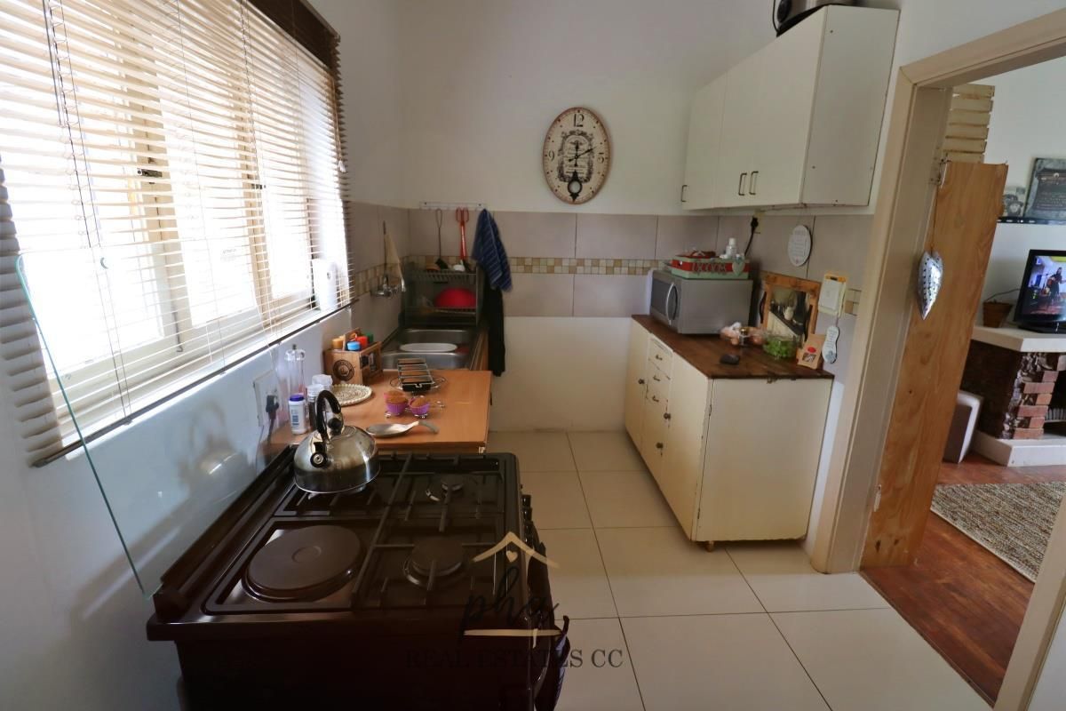 A compact kitchen featuring tiled flooring, built-in cabinetry, a gas stove, and a window with fitted blinds.