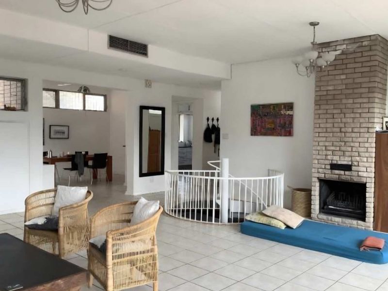 Spacious open-plan living area featuring a prominent brick fireplace, a central spiral staircase, and tiled flooring throughout.