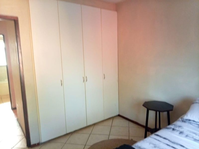 A bedroom featuring built-in cupboards and tiled flooring, providing functional storage space within the apartment.