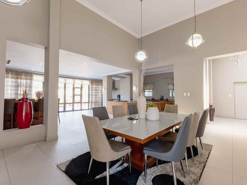 Spacious open-plan dining and living area featuring high vaulted ceilings, modern tiled flooring, and seamless flow into the adjacent kitchen space.