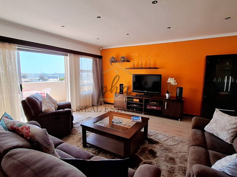 Spacious living room featuring laminate flooring, recessed downlighting, and large sliding glass doors providing access to the balcony.