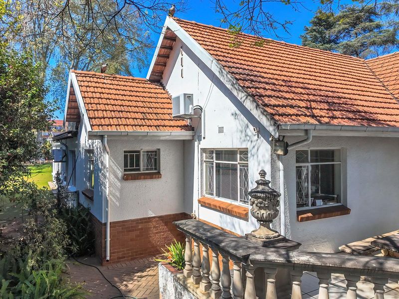 Rear exterior view of the office property featuring a terracotta tiled roof, stone balustrade, and paved patio area.