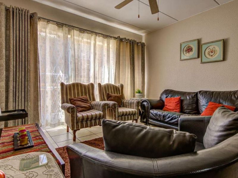 A comfortable living room featuring tiled flooring, a ceiling fan, and large sliding glass doors that provide natural light.