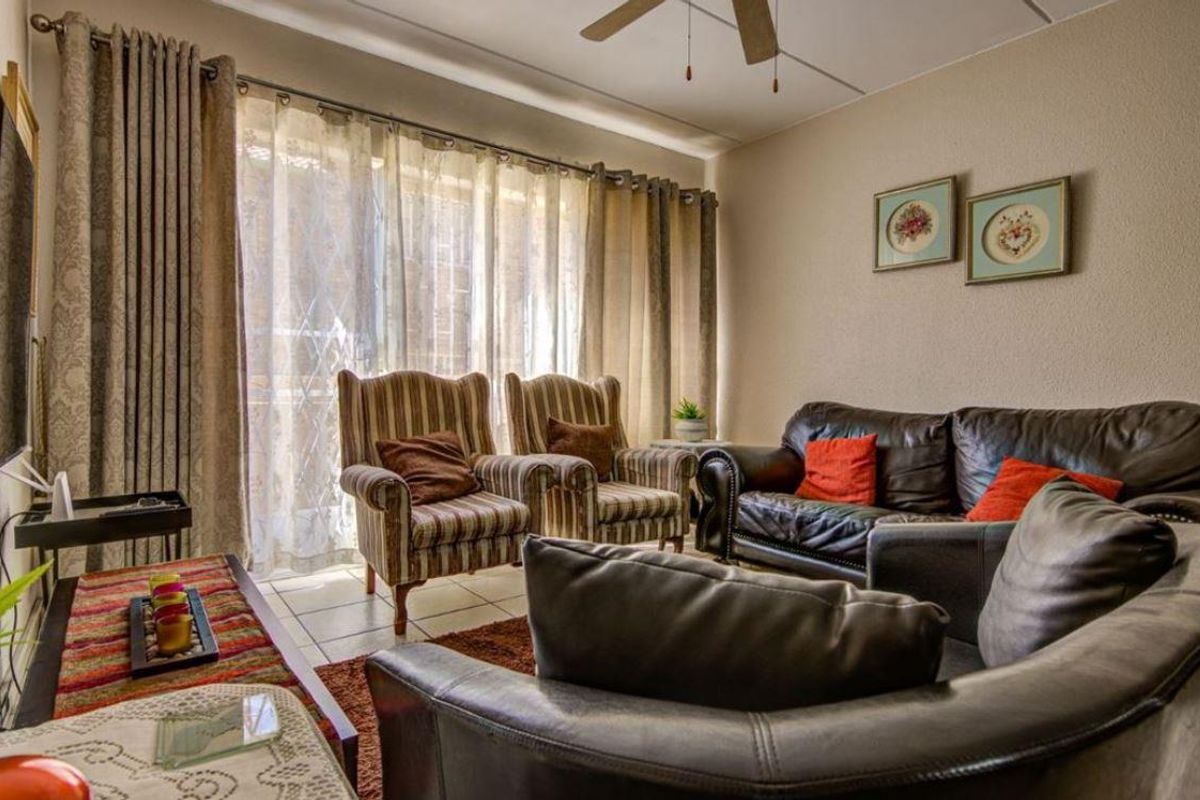 A comfortable living room featuring tiled flooring, a ceiling fan, and large sliding glass doors that provide natural light.